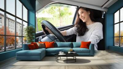 Asian women driving a car and smile happily with glad positive expression during the drive to travel journey, People enjoy laughing transport and relaxed happy woman on roadtrip vacation concept Wall mural