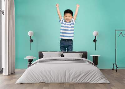 Cute Asian boy showing winner sign with his hands up isolated on green background Wall mural