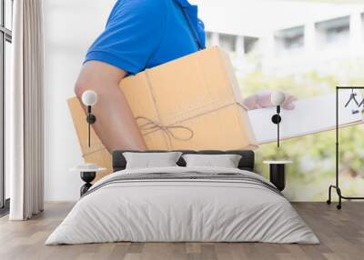 Delivery man holding a parcel box and white paper on clipboard Wall mural