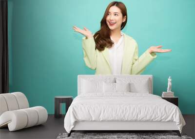 Happy Asian woman presenting or showing open hand palm with copy space for product isolated over green background Wall mural