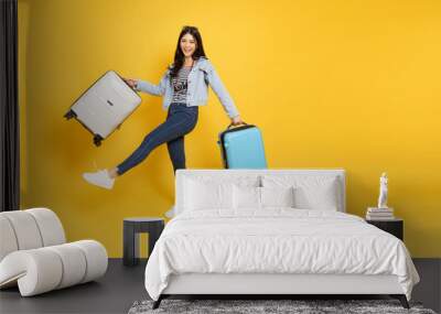 Happy Asian woman traveler standing and holding suitcase isolated on yellow background, Tourist girl having cheerful holiday trip concept, Full body composition Wall mural