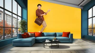 Portrait of happy excited Asian man office worker pointing hands to empty space on isolated yellow background, Full body composition and looking at camera Wall mural