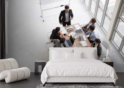 Top view of group of multiethnic busy people working in an office, Aerial view with businessman and businesswoman sitting around a conference table with blank copy space, Business meeting concept Wall mural