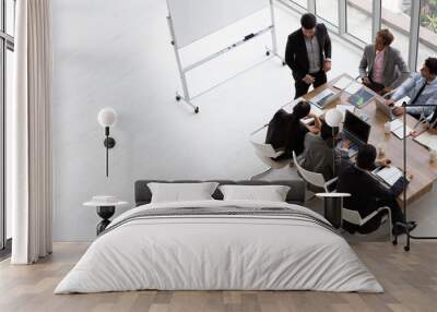 Top view of group of multiethnic busy people working in an office, Aerial view with businessman and businesswoman sitting around a conference table with blank copy space, Business meeting concept Wall mural