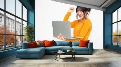 Young happy smiling Asian woman in yellow casual clothes holding laptop with chatting and laughing with friends online Wall mural