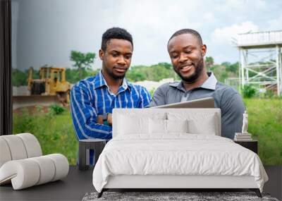 african agricultural businessmen, discussing using a laptop on a piece of land Wall mural