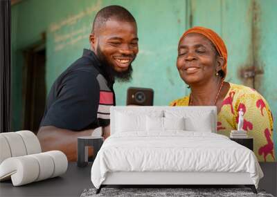 african man shows an old african woman interesting content on his phone Wall mural