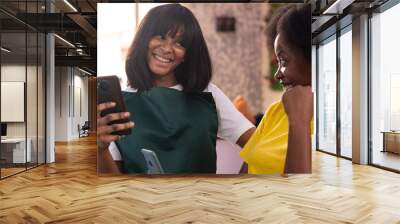 african women in a salon discuss while holding their phones Wall mural