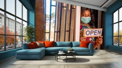 an african small business owner holding a open sign in front of her store Wall mural