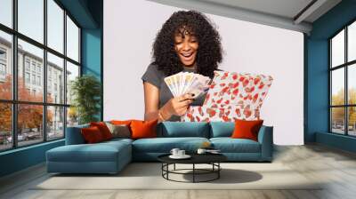 excited young black lady opens a gift box containing money Wall mural