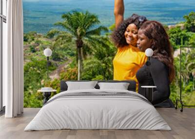 two young female african friends standing together outdoor on a hike through nature, feeling excited and happy Wall mural