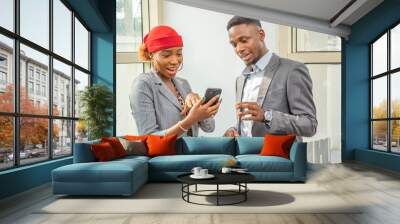 young african businesswoman and businessman having a meeting standing, viewing something on a mobile phone Wall mural