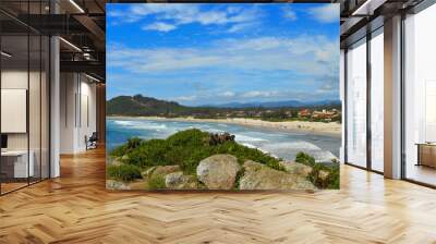 Panoramic view of Barra Garopaba beach, with rocks at the top of the viewpoint in the foreground. Wall mural