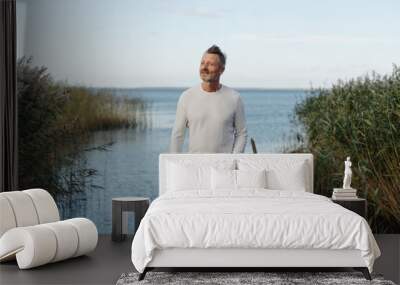 Attractive middle-aged man posing on a jetty Wall mural