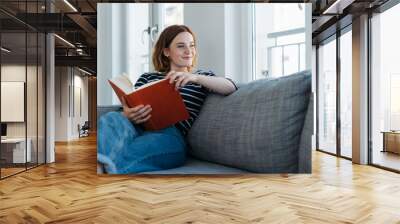 Casual trendy young woman relaxing with a book Wall mural