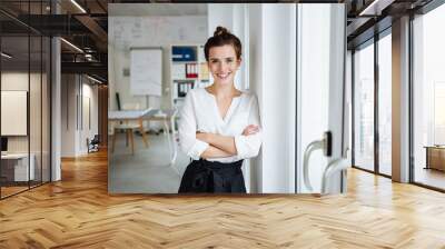 Confident young businesswoman looks at camera laughing Wall mural