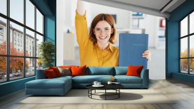 Excited young businesswoman cheering Wall mural