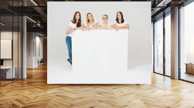 Four smiling female friends posing with a sign Wall mural