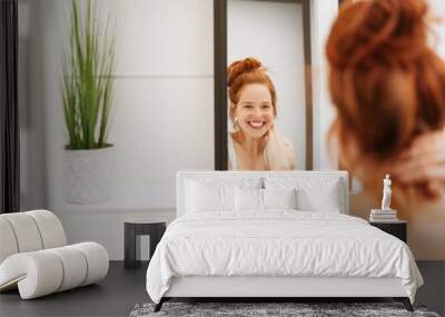 Happy young woman grinning at her reflection Wall mural