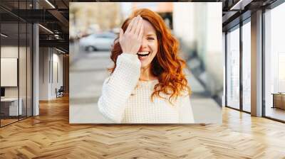 Laughing playful young woman covering one eye Wall mural