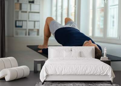 Man doing exercises, lying on back in office Wall mural