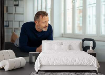 Man resting on a gym mat alongside a kettle weight Wall mural