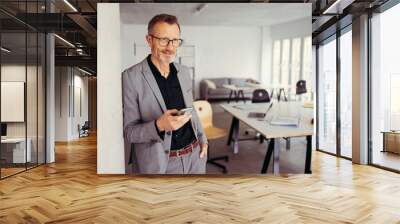 mature businessman standing with cellphone in modern office Wall mural