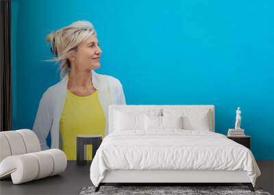 Relaxed confident blond woman against a blue wall Wall mural