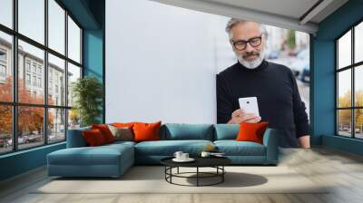 Smiling relaxed man reading a mobile message Wall mural