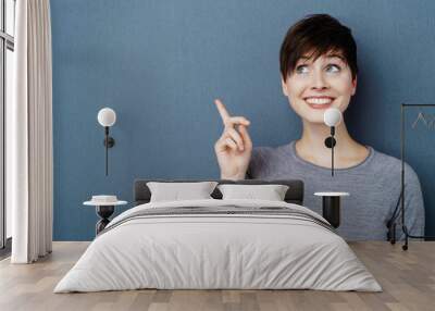 Studio shot portrait of cheerful woman pointing up Wall mural