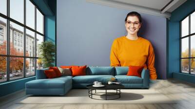 Vivacious young woman wearing glasses and an orange top Wall mural