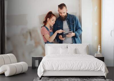 Young couple discussing data on a tablet together Wall mural