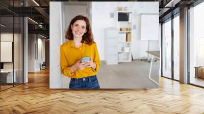 young modern business woman with cell phone laughs at camera Wall mural