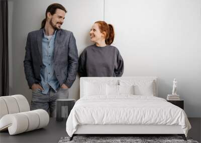 Young people stand in front of a white wall and look at each other Wall mural