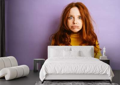 Young redhead woman looks frustrated at camera, copy space Wall mural