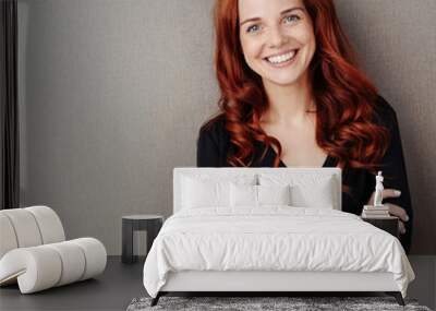 Young smiling red-haired woman with arms folded Wall mural