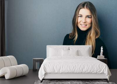 Young smiling woman against blue background Wall mural