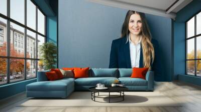 Young smiling woman standing against blue wall Wall mural