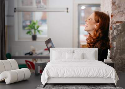 Young woman laughing at a good online joke Wall mural