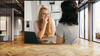 Young woman listening to a colleague with a smile Wall mural