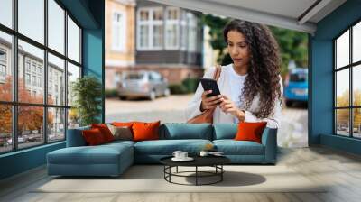 Young woman looking at her phone in consternation Wall mural