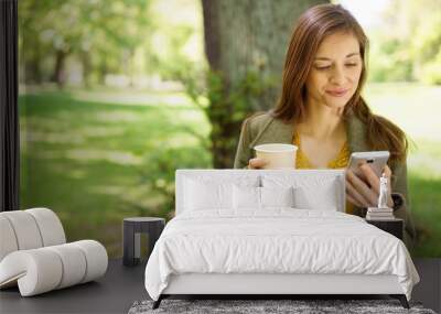 Young woman relaxing in a park with coffee Wall mural