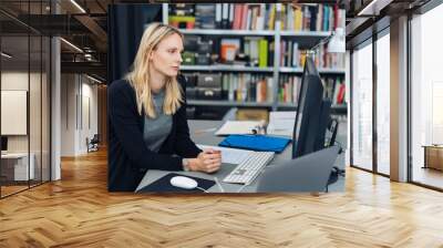 Young woman sitting working at a desktop computer Wall mural