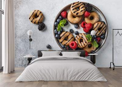 Homemade cinnamon and chocolate mini donuts on the plate with berries and mint on the light grey backgorund Wall mural