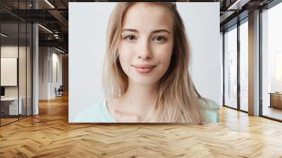 Beautiful female having dark shining eyes, pure skin and blonde straight hair wearing loose sweater looking directly at camera having mysterious and glad expression. Face expressions and emotions Wall mural