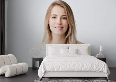 Beautiful female looks at camera having her blonde hair loose wearing loose sweater biting her lip, building plans, thinking about something, making decision. Face expression, feelings and attitude Wall mural