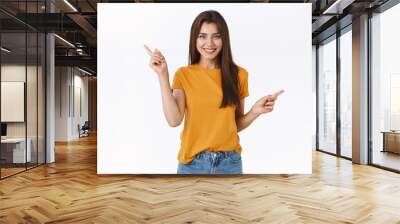 Carefree, happy smiling girl in yellow t-shirt shopping with confident relaxed expression, pointing sideways left and right as making choice, asking advice or suggestions what better buy Wall mural