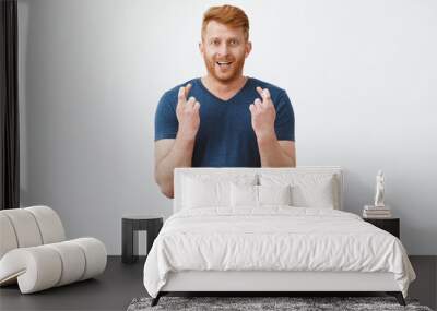 Come one guys I believe in you. Handsome masculine redhead male model feeling nervous standing with fingers crossed, staring at camera, watching important match and making bet, hoping to win Wall mural