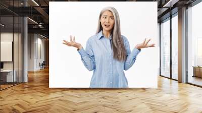 Confused japanese middle aged woman looking questioned and frustrated, shrugging shoulders with disappointed face expression, asking what, standing over white background Wall mural