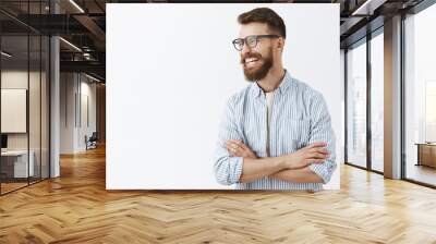 Creative happy and funny bearded man with moustache in glasses with black rim turning left laughing out loud enjoying interesting and hilarious conversation holding hands crossed on chest relaxed Wall mural